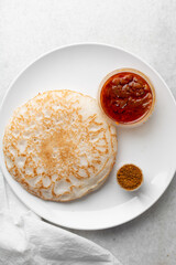 Overhead view of a plate of sinasir and pepper sauce, top view of food from northern nigeria sinasir rice pancake and stew, nigerian ethnic foods