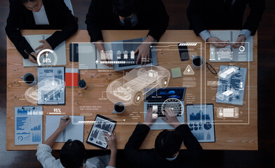 A top view of a business meeting focusing on car design, featuring digital graphics, charts, and data analysis. Teamwork and collaboration are evident in this modern office setting. Trope