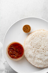 Overhead view of a plate of sinasir and pepper sauce, top view of food from northern nigeria sinasir rice pancake and stew, nigerian ethnic foods