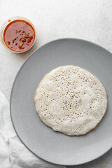 Overhead view of a plate of sinasir and pepper sauce, top view of food from northern nigeria sinasir rice pancake and stew, nigerian ethnic foods
