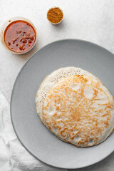Overhead view of a plate of sinasir and pepper sauce, top view of food from northern nigeria sinasir rice pancake and stew, nigerian ethnic foods