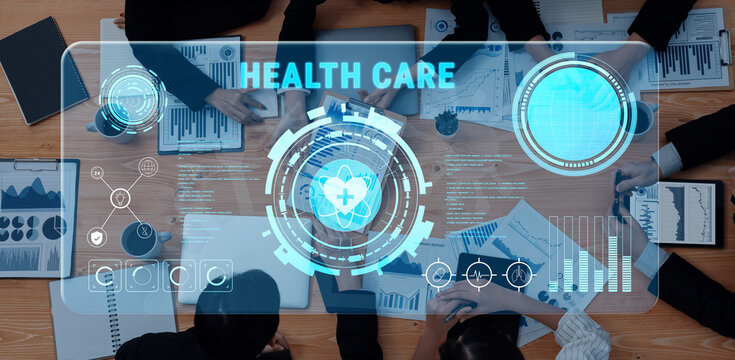 A professional team collaborates in a modern office setting using advanced technology for data analysis in health care. Digital interfaces illustrate health statistics. Trope - Powered by Adobe