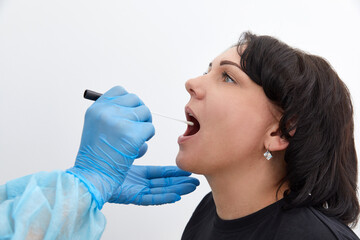 Doctor in a protective suit taking a throat and nasal swab from a patient to test for possible...