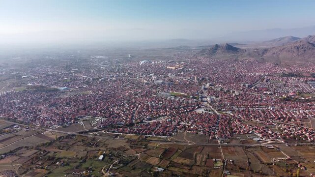 Person paragliding over eastern european town. Aerial drone video of Prilep in North Macedonia.