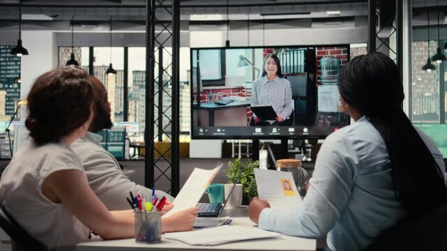 Recruiters and applicant engage in a virtual call conversation using webcam and high tech tools, reviewing resume and assessing job search progress during remote interview conference. Camera A.