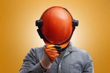 Industrial worker wearing orange safety helmet with headlamp and protective gloves on an orange background. Concept of construction, engineering, workplace safety.