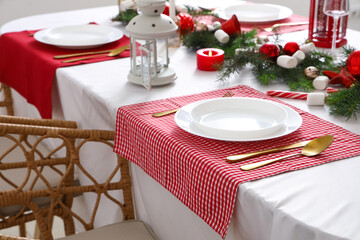 Festive table setting with clean plates, cutlery and Christmas decorations
