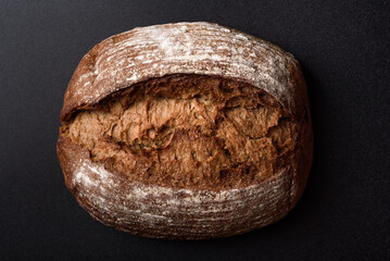 Dark rye sourdough bread on black background, high angle view