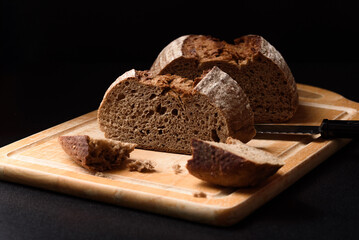 Dark rye sourdough bread sliced on black background