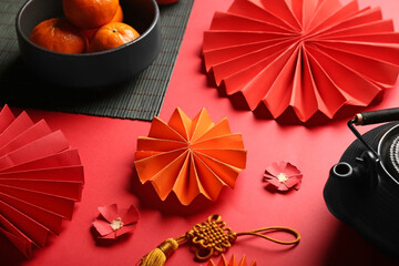 Teapot with mandarins and oriental symbols on red background. New Year celebration