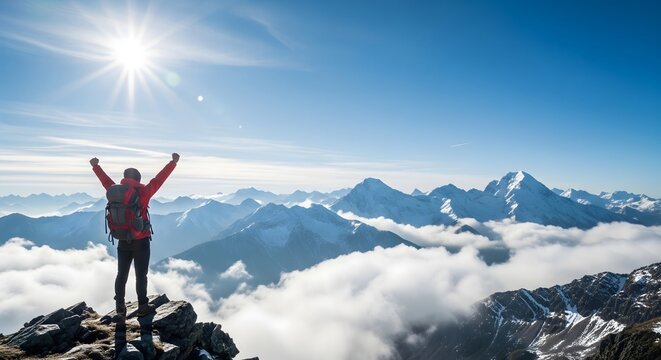 Hiker celebrating victory on snowy mountain peak, adventure travel success, achievement and freedom concept with sunlight, blue sky, and panoramic view of majestic alpine mountain landscape.
