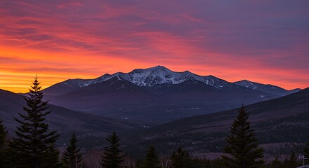 Obraz premium Majestic mountain range silhouetted by a fiery sunset sky