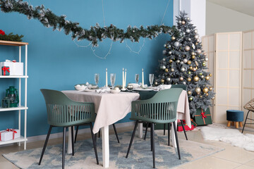 Interior of festive room with Christmas tree, decorations and served dining table