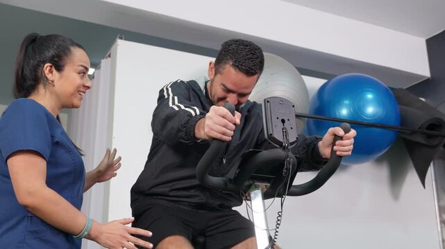 Physical therapist helping patient doing exercise on stationary bike
