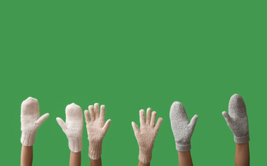 Female hands in warm gloves and mittens on green background