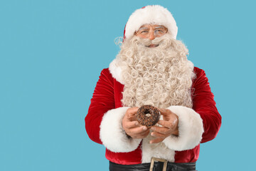 Santa Claus with tasty donut on blue background