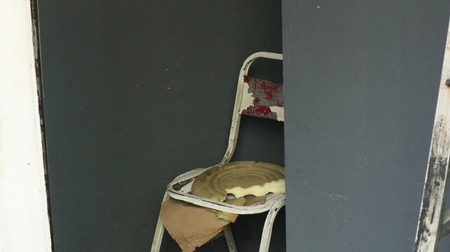 a broken chair made of iron that the owner keeps in the warehouse. Even though it is broken, sometimes people still like to sit on this chair even though it is uncomfortable.