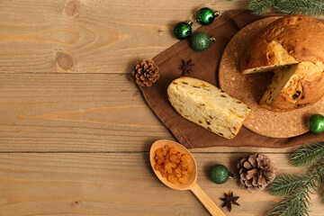 Cork board with cut Panettone and Christmas decor on wooden background