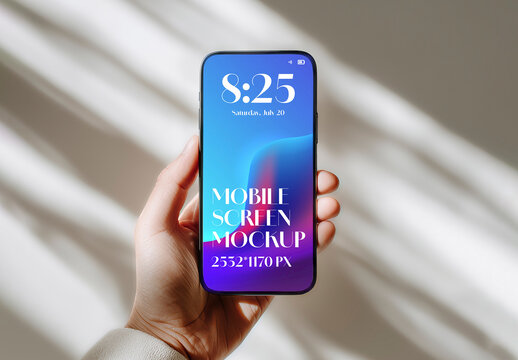 Hand holding a modern smartphone with a blank screen for a mockup against a wall with window shadows