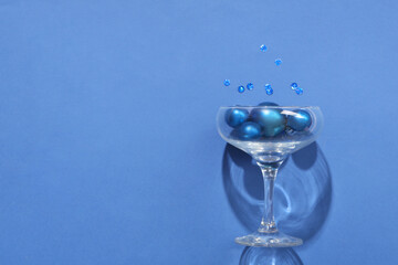 Champagne glass with Christmas balls and glitters on blue background
