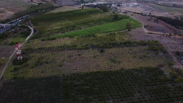 Aerial View of Agricultural Fields, Dirt Road, and Highway at Sunset: Rural Landscape with Lush Greenery and Infrastructure