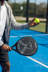 Man holding padel racket and ball on court