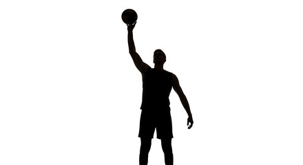 Silhouette of a basketball player in mid-air, preparing to shoot a basketball.