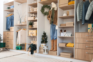 Modern wardrobe with stylish winter clothes, Christmas decorations and gift boxes