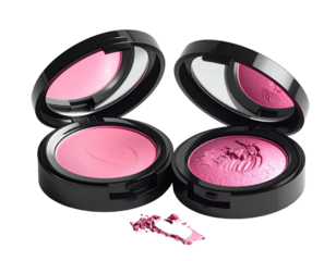 Two opened compacts with pink blush and a scattering on a dark background