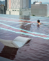 Man swimming in infinity roof top pool.