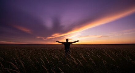 Silhouette of a person with arms outstretched embracing a dramatic sunset in a field