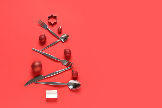 Christmas tree made of stainless cutlery and decorations on red background - Powered by Adobe
