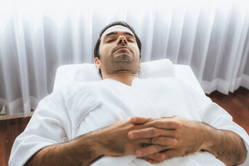 Obraz premium Caucasian man customer enjoying relaxing anti-stress spa massage and pampering with beauty skin recreation leisure in day light ambient salon spa at luxury resort or hotel. Quiescent