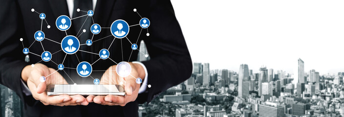A professional businessman holding a tablet showcasing digital network connections with a cityscape background, illustrating modern technology and collaboration concepts. Tessel