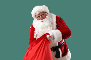 Santa Claus with Christmas bag on green background