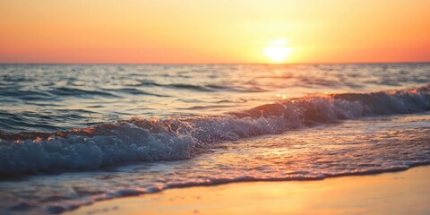 Fototapeta premium A serene beach scene with a vibrant sunset, calm waves, and a golden sand beach under a clear sky.