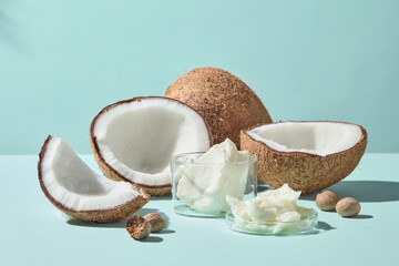 Half coconut shells, shea butter chunks, and creamy butter placed on clean pastel surface, styled for skincare, spa, wellness, and organic cosmetic promotional images.