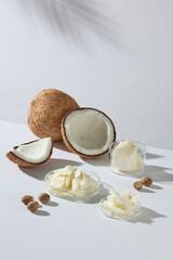 Vertical composition of coconut, shea butter, and seeds arranged together on a white surface, ideal for skincare concept, product advertising, and design layouts.