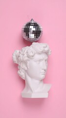 A white statue head and disco ball on pink