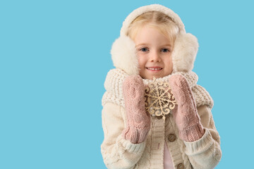 Cute little girl in winter clothes with snowflake on blue background