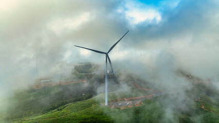Aerial view of Wind turbines amidst misty landscape at sunset in Da lat, Vietnam
