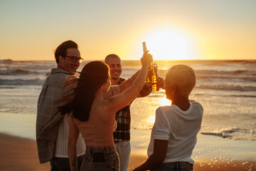 Friends toasting drinks at beach during sunset