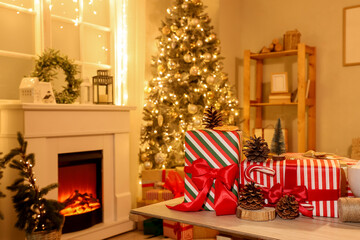Christmas presents with fir cones on table in living room at night, closeup
