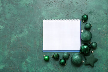 Notebook with Christmas balls on green grunge background
