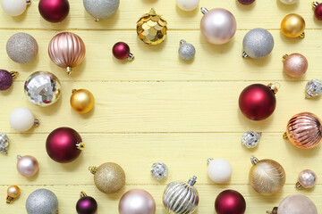 Frame made of different Christmas balls on beige wooden background