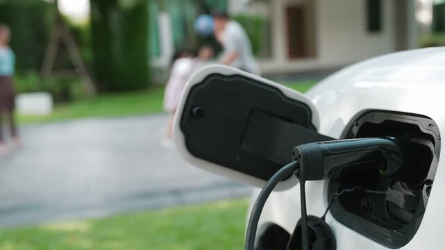 Progressive parent have returned from picking up daughter at school with concept of electric vehicle and renewable energy, charging station for EV car at home. Alternative eco transportation.