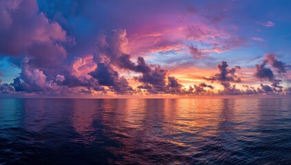 The sun sinks into the calm ocean, painting the sky in glowing hues of orange, pink, and purple with clouds reflecting the evening light.
