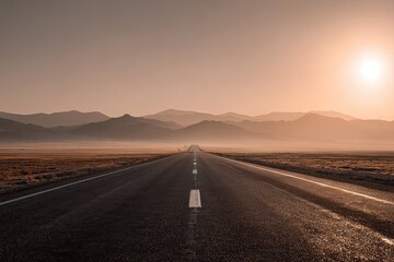 Fototapeta premium Empty highway stretching to distant mountains under a sunrise