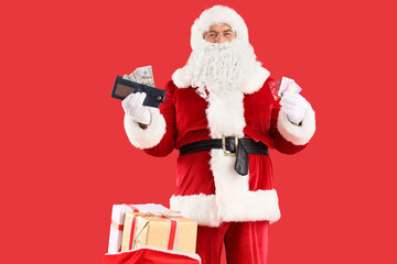 Santa Claus holding gift cards, wallet and bag with boxes on red background. Christmas celebration
