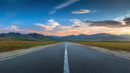 Naklejka premium Asphalt road stretches into a vibrant mountain landscape at sunset